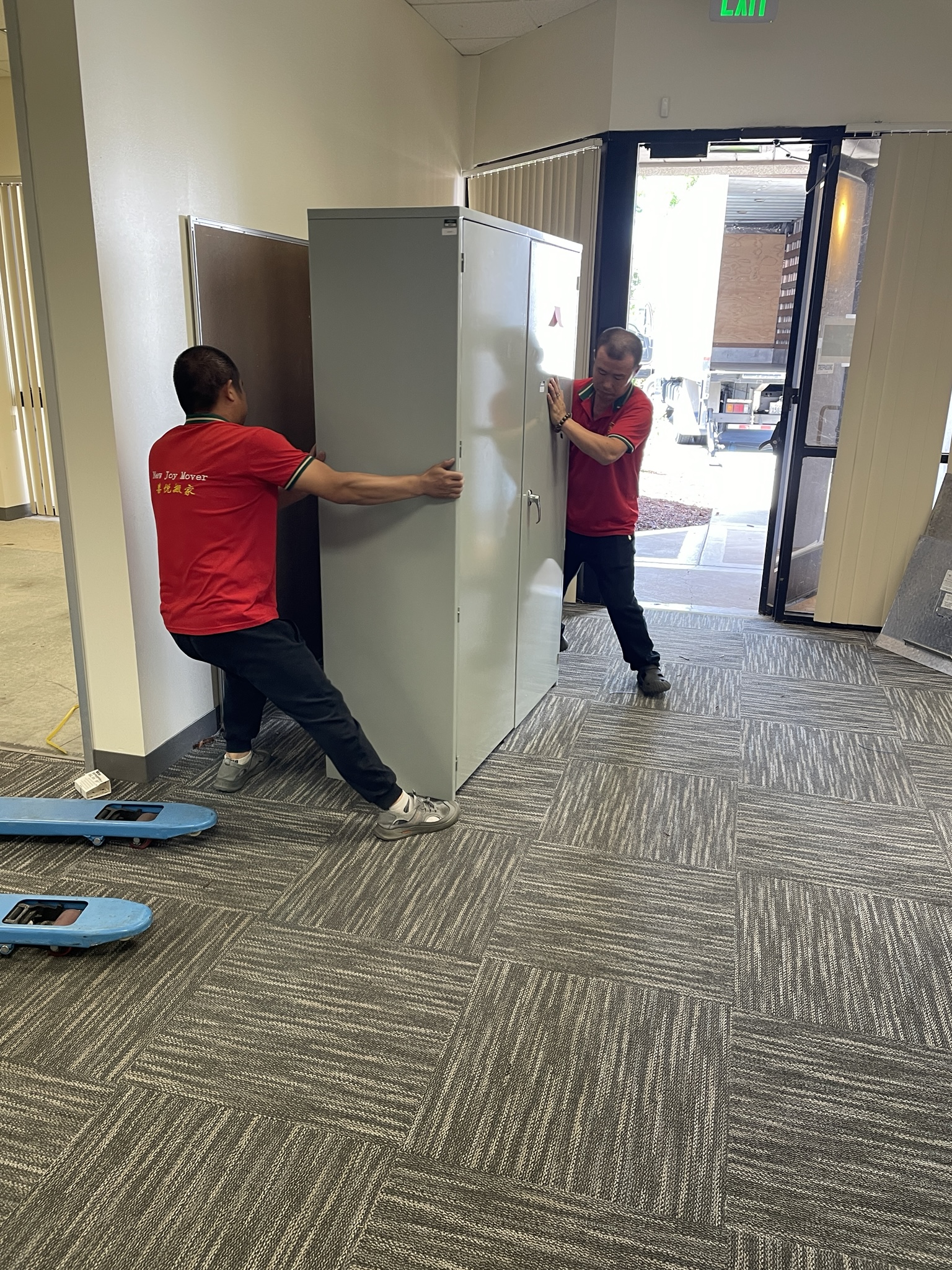 New Joy Moving movers carrying furniture through a building hallway