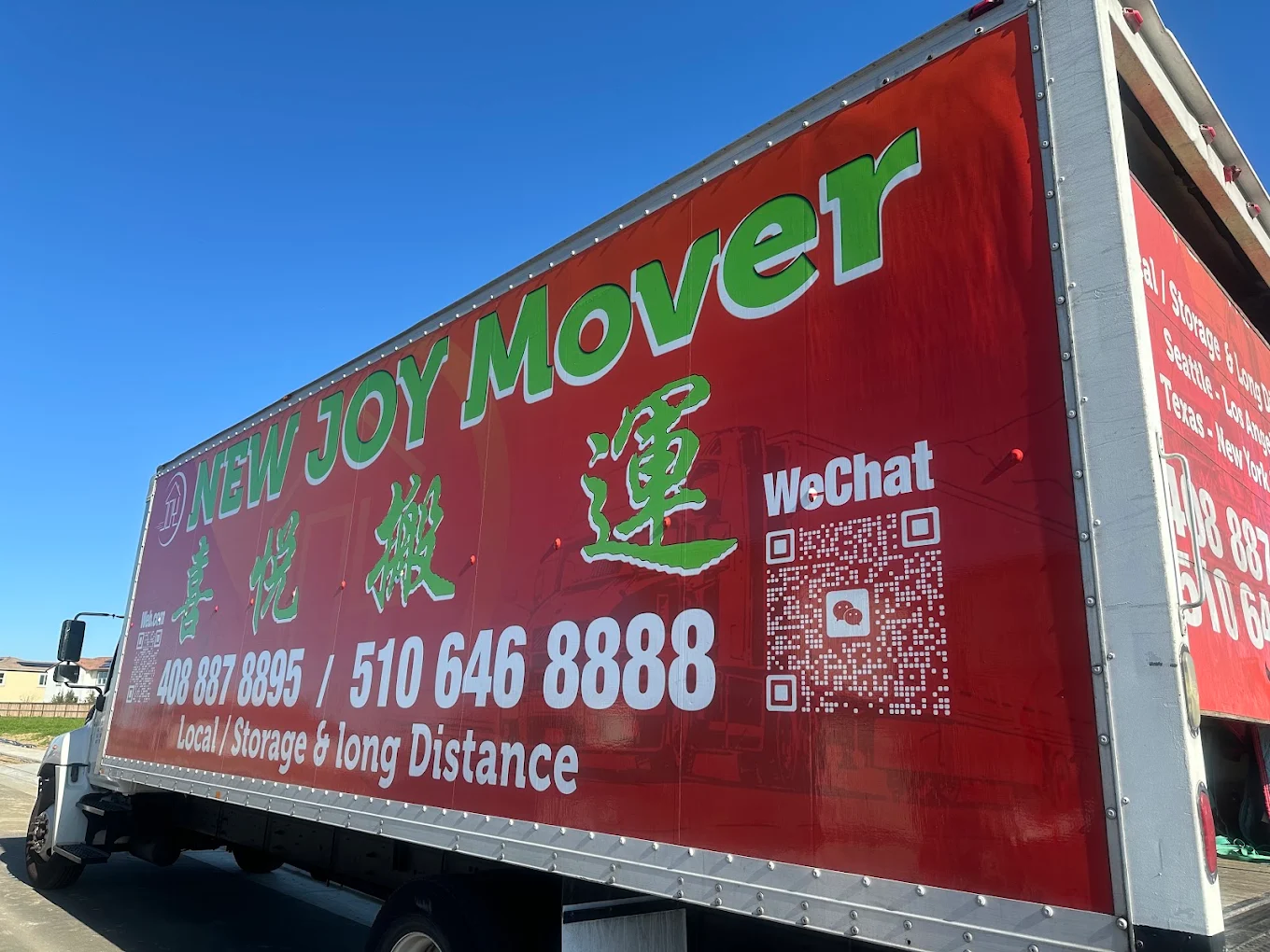 New Joy Moving red branded truck parked under a blue sky